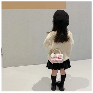 Rear view of a girl wearing a pink bow purse with white flowers and pearl handle