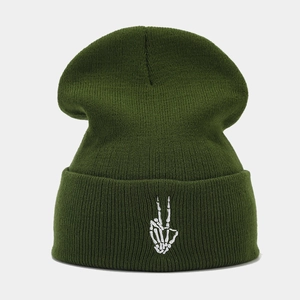 Détail de la broderie main de squelette blanche sur un bonnet en tricot vert foncé