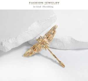 Detailed back view of vintage dragonfly brooch with pin clasp and golden texture
