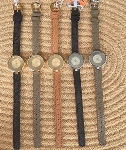 Vertical lineup of minimalist women watches with leather bands on woven texture