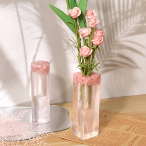 Detail of gradient pink resin flower vases in rectangular and cylindrical shapes on a desk