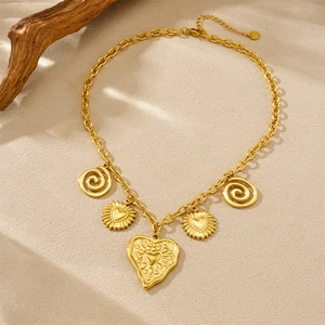 Gold stainless steel chain necklace with heart and spiral pendants on beige background