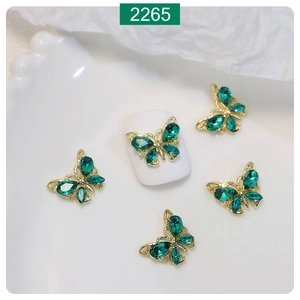 Detail of 3D butterfly nail charms with golden alloy frame and emerald green crystals