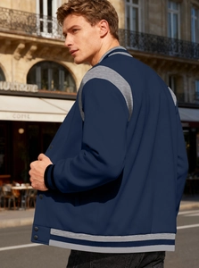 Rear view of navy blue and grey varsity jacket on a model in a European street setting
