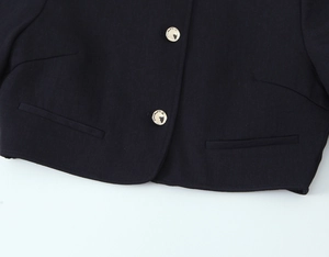Detailed close-up of navy blue jacket featuring gold embossed buttons and welt pockets