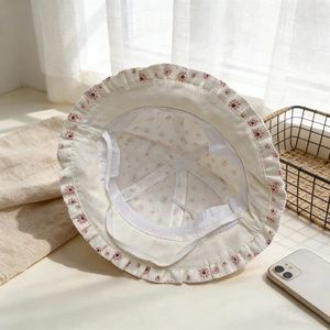 Détail d'un chapeau de soleil bébé avec broderie florale rose et bordure festonnée