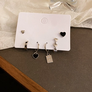 Close-up of a 6-piece silver heart earring set featuring Love More engraving and black enamel