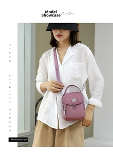 Detail view of pink nylon crossbody bag with multi-zipper layers and branded strap
