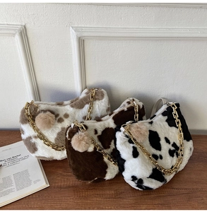 Three plush faux fur tote bags with cow prints in black and brown with gold chain straps