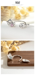 Detail showing silver C-shaped wing earrings with pink and blue star-shaped gemstones