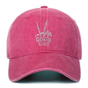 Detailed white embroidery of skeletal peace sign and Good Vibes text on a washed red cap