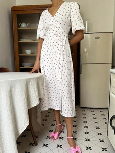 Detail of white cotton wrap dress with red floral print and waist tie detail