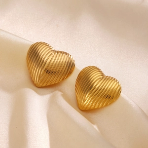 Chic heart-shaped gold studs with ribbed texture on champagne satin background