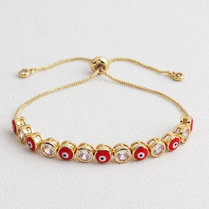 Macro detail of adjustable gold evil eye bracelet with red enamel and clear zircon stones