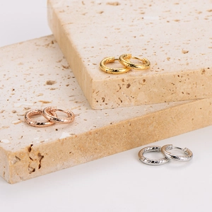 Three pairs of geometric stainless steel hoop earrings with twist patterns in gold and silver