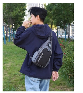 Outdoor back view of a grey and black waterproof crossbody chest bag on a model