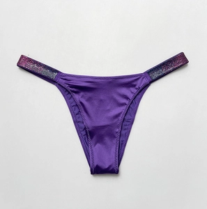 Macro detail of purple satin thong with colorful rhinestone side straps and low-rise cut