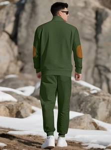 Rear view of dark green men's knitted tracksuit with elbow patch details on rock terrain
