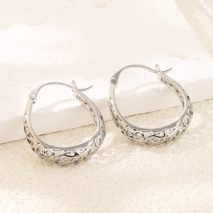 Silver hollow out teardrop hoop earrings with vintage engraved patterns on stone background