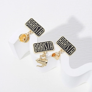 Macro shot of three gold barista enamel pins with coffee dripper and kettle charms