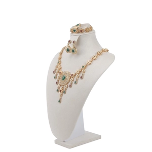Detailed view of luxury gold necklace set with green and red gems on a jewelry bust