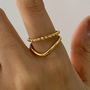 Detail of gold stacked rings with twisted rope design and smooth wavy band on finger