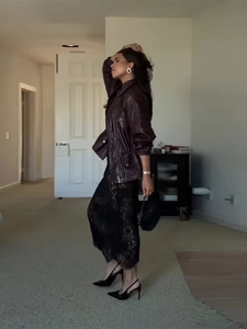 Street style look of burgundy leather jacket paired with black lace skirt and heels