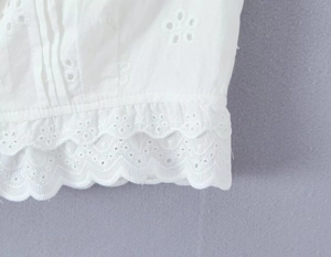 Gros plan détaillé de la dentelle brodée blanche et des bords festonnés sur un haut