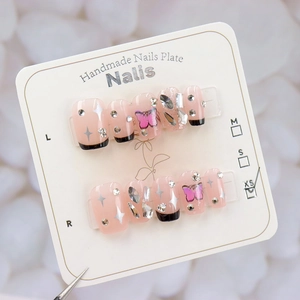 Détail de faux ongles roses avec motifs papillon, étoiles d'argent et strass sur carte