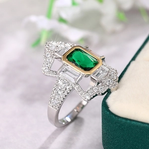 Primer plano del anillo de esmeralda rectangular con diamantes en fondo de mármol