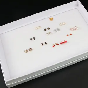 White multi-slot earring display box set with various jewelry studs and heart patterns