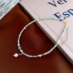 Detail of Amazonite beaded anklet with pearls and gold metal clasp on brown background