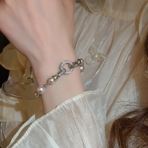 Gros plan d'un bracelet en perles avec fermoir en zircon porté sur une manche en dentelle
