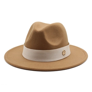 Close-up of camel wool fedora with beige ribbon and gold circular brand logo metal buckle