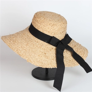 Detail of wide brim straw hat featuring natural texture and an elegant black bow ribbon