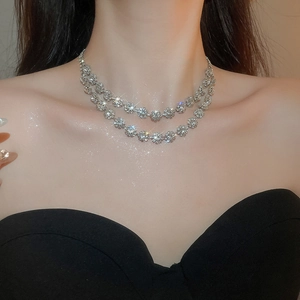 Detail of silver double-layered diamond flower necklace worn on an elegant model
