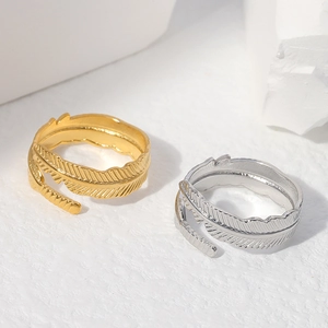 Adjustable titanium steel feather ring set in gold and silver finish on stone background