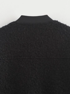Detailed close-up of high-quality black faux shearling fabric and ribbed collar on jacket