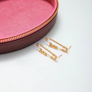 Boucles d'oreilles trombone dorées avec lettrage LOVE et strass blancs sur fond blanc