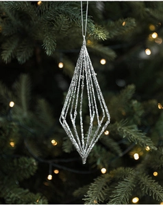 Close-up of silver glitter geometric hollow diamond ornament on green Christmas tree branch