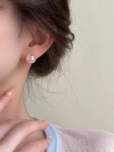 Close-up of pink mermaid pearl stud earrings with iridescent glow on model's ear