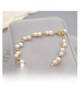 Detail of freshwater pearls and gold metal beads on an elegant bracelet with lobster clasp
