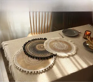 Detail of round mandala jute placemats with tassel edges in a cozy dining setting