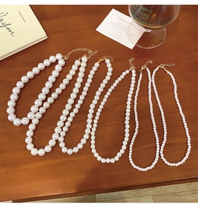 French vintage pearl necklace detail showing five various bead sizes on a wooden desk