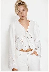 Close-up of white long sleeve top featuring intricate eyelet embroidery and tie-front detail