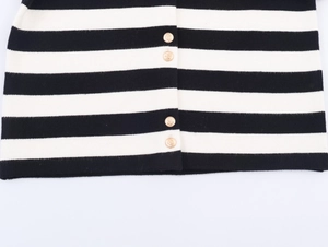Detailed view of black and white striped knitwear with decorative gold buttons