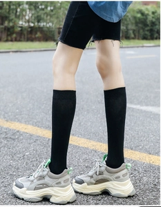 Detail of chicken leg socks worn with grey sneakers on asphalt road background