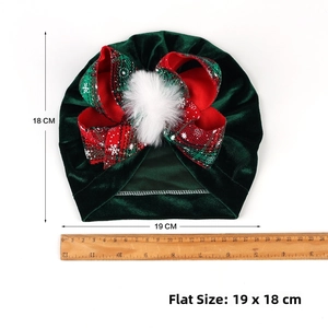 Flat lay of dark green velvet baby turban hat with sizing ruler showing 19x18 cm dimension