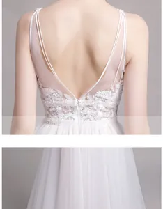 Détail d'une robe de mariée en dentelle blanche avec dos nu en V et boutons en perles