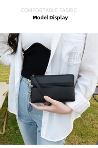 Women's black rectangular clutch with double zippers and wristlet shown outdoors